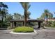 Elegant gated entrance with a roundabout, beautiful landscaping, and mature palm trees at 7400 E Gainey Club Dr # 222, Scottsdale, AZ 85258