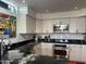 A modern kitchen featuring black marble countertops, stainless steel appliances, and light wood cabinets at 7400 E Gainey Club Dr # 222, Scottsdale, AZ 85258