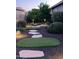 Landscaped backyard with stone pathway, artificial turf, and lighting at 9364 W Cashman Dr, Peoria, AZ 85383