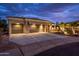 Night view of a three-car garage; well lit with flag and landscaping at 13286 W Micheltorena Ct, Sun City West, AZ 85375