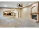 Open-concept living room with a fireplace, ceiling fan, and view of the kitchen at 22852 N 103Rd Ave, Peoria, AZ 85383