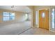 Bright living room featuring fresh carpet, a modern light fixture, and a decorative front door at 22852 N 103Rd Ave, Peoria, AZ 85383