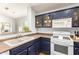Charming kitchen featuring ample countertop space, white appliances, and dark blue cabinetry at 44520 W Windrose Dr, Maricopa, AZ 85138