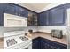 Efficient kitchen layout with white appliances and dark blue cabinetry at 44520 W Windrose Dr, Maricopa, AZ 85138