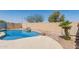 Backyard swimming pool with baja step, rock waterfall feature, and surrounding block wall at 44520 W Windrose Dr, Maricopa, AZ 85138