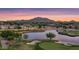 Scenic aerial view of a golf course community with a lake and mountain backdrop at sunset at 6675 S Giralda Ave, Gilbert, AZ 85298