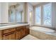 Elegant bathroom featuring a large vanity, soaking tub, and glass block shower at 8037 E Thorntree Dr, Scottsdale, AZ 85266