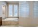 Relaxing bathroom with a corner soaking tub and glass block shower enclosure at 8037 E Thorntree Dr, Scottsdale, AZ 85266