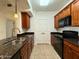 Galley kitchen with stainless sink, granite counters, wood cabinets, and black appliances at 10136 E Southern Ave # 1110, Mesa, AZ 85209