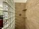 This tiled shower features a glass block wall, a shower head, and built-in shelving at 10136 E Southern Ave # 1110, Mesa, AZ 85209