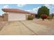 Tan house with a two-car garage and nicely landscaped yard at 16220 W Red Rock Dr, Surprise, AZ 85374