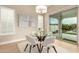 Dining area with a round glass table, white chairs, modern light fixture, and sliding glass door to the patio at 16639 W Pinchot Ave, Goodyear, AZ 85395