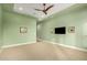 Spacious living room featuring soft carpet, ceiling fan, tray ceiling, and a soothing green color scheme at 16639 W Pinchot Ave, Goodyear, AZ 85395