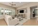 Comfortable living room featuring a white sofa, large windows, and a ceiling fan above a glass table at 16639 W Pinchot Ave, Goodyear, AZ 85395