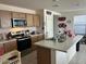 Well-lit kitchen features an island, light wood cabinetry, tile flooring, and stainless steel appliances at 18225 W Yavapai St, Goodyear, AZ 85338