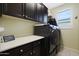 Laundry room with dark cabinets, washer, dryer, and ample counter space at 2005 N 169Th Ave, Goodyear, AZ 85395