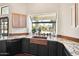 This bright kitchen features granite countertops, a copper sink, modern appliances, and a large window overlooking the backyard at 5582 W Aster Dr, Glendale, AZ 85304