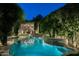 Beautiful backyard pool area at night with lush landscaping and cozy dining space at 6529 E Camino De Los Ranchos St, Scottsdale, AZ 85254