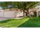 Front view of a tan house with a large tree and walkway at 9127 W Kimberly Way, Peoria, AZ 85382