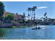 Idyllic lake view featuring calm waters, waterfront homes, and people enjoying a peaceful canoe ride at 10206 N 105Th Way, Scottsdale, AZ 85258