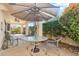 Covered patio area with an umbrella-covered table and lush landscaping at 10206 N 105Th Way, Scottsdale, AZ 85258