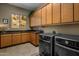 Laundry room with wood cabinets, granite countertops, and modern appliances at 11501 E Mark Ln, Scottsdale, AZ 85262