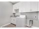 Functional laundry room with white cabinets, granite counters, and a modern washer at 1628 E Magellan Dr, New River, AZ 85087