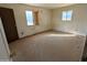 Bedroom with two windows, damaged walls, and worn flooring at 33767 W Grande Rd, Stanfield, AZ 85172