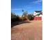 Large backyard featuring a brick-paved patio, gravel area, and a red fence under a bright blue sky at 4947 E Adobe St, Mesa, AZ 85205