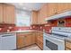 Kitchen with wood cabinets, white appliances, and red tile at 5804 E Dallas St, Mesa, AZ 85205