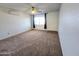 Bright living room featuring neutral carpet, ceiling fan, window, and wall-mounted air conditioning unit at 6815 W Reade Ave, Glendale, AZ 85303