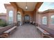 Inviting covered front entrance with elegant double doors and stone accents, showcasing a welcoming outdoor seating area at 9015 E Hackamore Dr, Scottsdale, AZ 85255