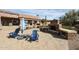 Backyard area with stone fireplace, desert landscaping, and comfortable blue Adirondack chairs and table at 9015 E Hackamore Dr, Scottsdale, AZ 85255