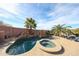 Beautiful pool and spa with rock waterfall feature, surrounded by mature palm trees and a spacious patio area at 9015 E Hackamore Dr, Scottsdale, AZ 85255