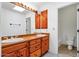 Dual sink vanity with decorative lighting fixtures, wood cabinets, and access to the bathroom at 9980 E Charter Oak Rd, Scottsdale, AZ 85260