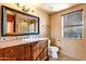 Bathroom featuring tile flooring, wood vanity, framed mirror, and a window for natural light at 9980 E Charter Oak Rd, Scottsdale, AZ 85260