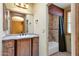 Bathroom featuring wood vanity, stone countertop, and decorative tile wall accents in the shower at 9980 E Charter Oak Rd, Scottsdale, AZ 85260