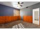 Bedroom with carpet, accent walls, wood paneled wainscotting and ceiling fan at 9980 E Charter Oak Rd, Scottsdale, AZ 85260