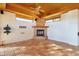 Bright living room featuring a stone fireplace, wood ceiling, and large windows at 9980 E Charter Oak Rd, Scottsdale, AZ 85260