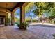 Covered patio with red brick tile flooring, beautiful green plants and an arch that looks out into the yard at 9980 E Charter Oak Rd, Scottsdale, AZ 85260