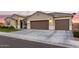 Tan house with three-car garage, landscaping, and a paved driveway at 1061 W Descanso Canyon Dr, Casa Grande, AZ 85122