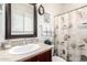 Well-lit bathroom featuring a seashell-themed shower curtain, neutral countertops, and a dark framed mirror at 14765 W Alexandria Way, Surprise, AZ 85379