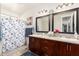 Well-lit bathroom with double sinks, modern vanity, and a decorative shower curtain at 14765 W Alexandria Way, Surprise, AZ 85379