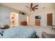 A corner view of a neutral main bedroom with a plush king bed and large decorative ceiling fan at 1716 S 141St Pl, Gilbert, AZ 85295