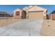 New construction home with a tan exterior, two-car garage, and desert landscaping at 23256 W Miami St, Buckeye, AZ 85326