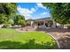 Expansive backyard featuring lush green lawn, mature trees, and a charming covered patio area, perfect for outdoor entertaining at 300 N Portland Ave, Gilbert, AZ 85234