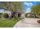 Stunning single-story home with circular drive, lush landscaping, and mature trees on a sunny day at 300 N Portland Ave, Gilbert, AZ 85234