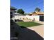 The backyard features a small artificial turf lawn, desert landscaping, and a white privacy fence with a black wooden gate at 3021 N 47Th St, Phoenix, AZ 85018