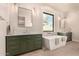 Modern bathroom with a soaking tub, dual vanities, and sleek, dark green cabinetry at 3021 N 47Th St, Phoenix, AZ 85018