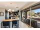 Modern kitchen and dining area with dark cabinetry, a stone countertop island, pendant lighting, and access to the patio at 10260 E White Feather Ln # 1038, Scottsdale, AZ 85262